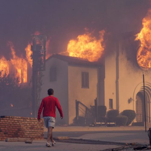 A man walks in front of the burning Altadena Community Church, Wednesday, Jan. 8, 2025, in the downtown Altadena section of Pasadena, Calif. (AP Photo/Chris Pizzello)